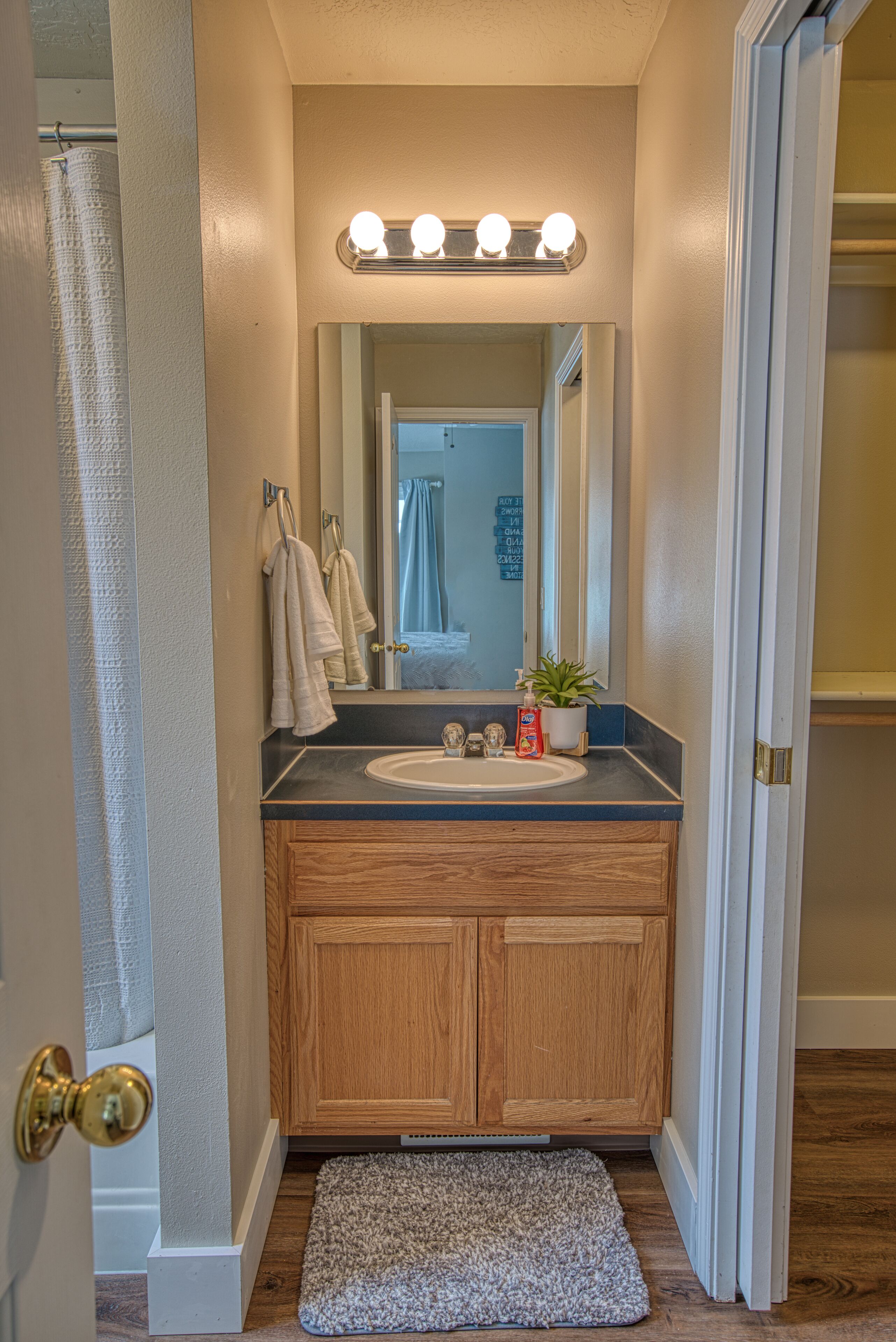 A bathroom with a wooden vanity, a sink, a mirror, and a light fixture above the mirror.