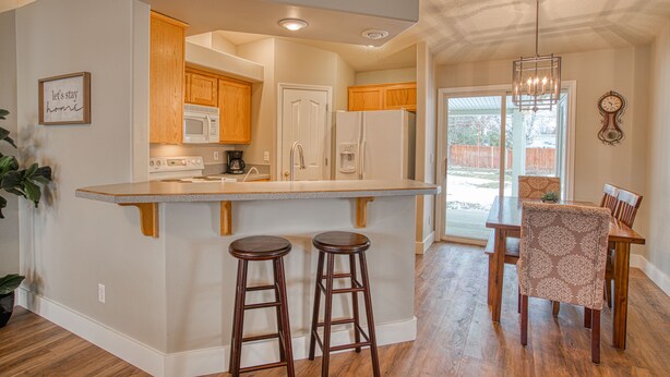 A kitchen with wooden cabinets, a white refrigerator, and a built-in microwave. There are two wooden stools at the kitchen island. - Cozy and Stylish Home (Boise)