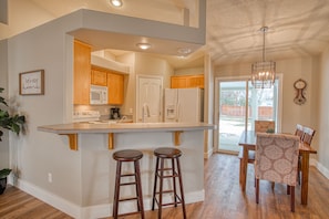 A kitchen with wooden cabinets, a white refrigerator, and a built-in microwave. There are two wooden stools at the kitchen island.