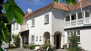 A two-story building with a white facade, multiple windows, and a balcony. - Hotel Villa Strand (Hornbaek)