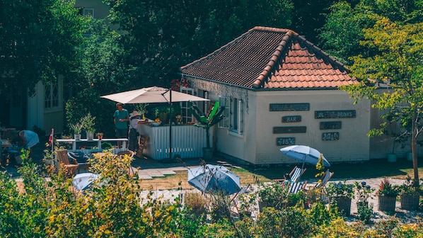 A villa with a tiled roof, outdoor seating, and a bar area. - Hotel Villa Strand (Hornbaek)