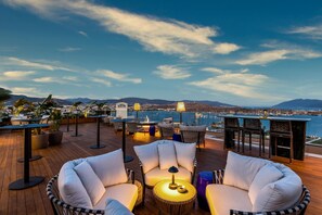 Une terrasse sur le toit avec des sièges extérieurs, une vue sur la mer et les montagnes au loin.