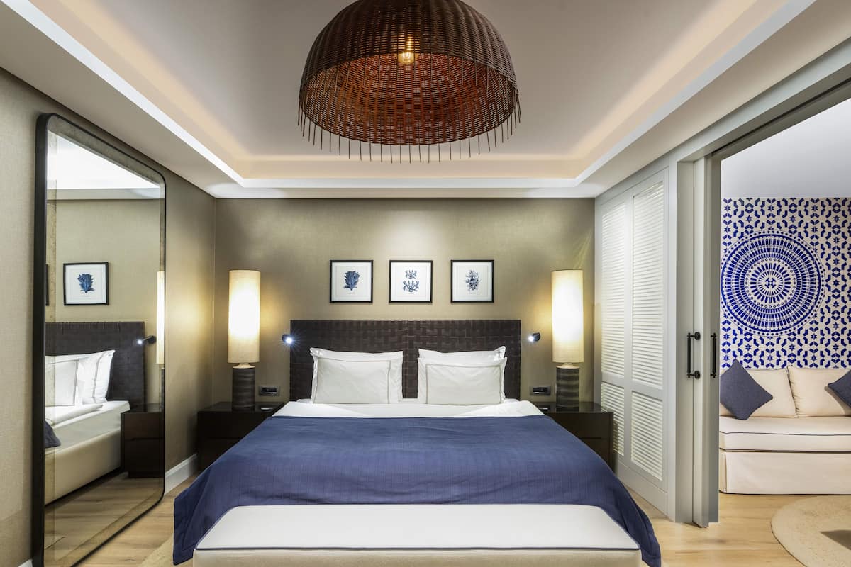 Une chambre d’hôtel moderne avec un grand lit, des lampes de chevet, un miroir et un mur décoré d’un motif.