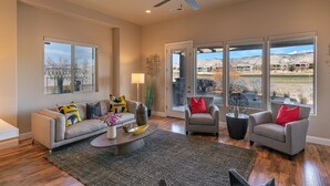 A spacious living room with a sofa, armchairs, and a coffee table. - Modern 3BR on the 18th Green - Golf Course Views (St. George)