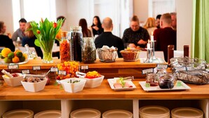 A buffet table with various food items and condiments, surrounded by guests.