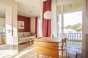 Een kamer met een houten tafel, een bank en uitzicht op een balkon.