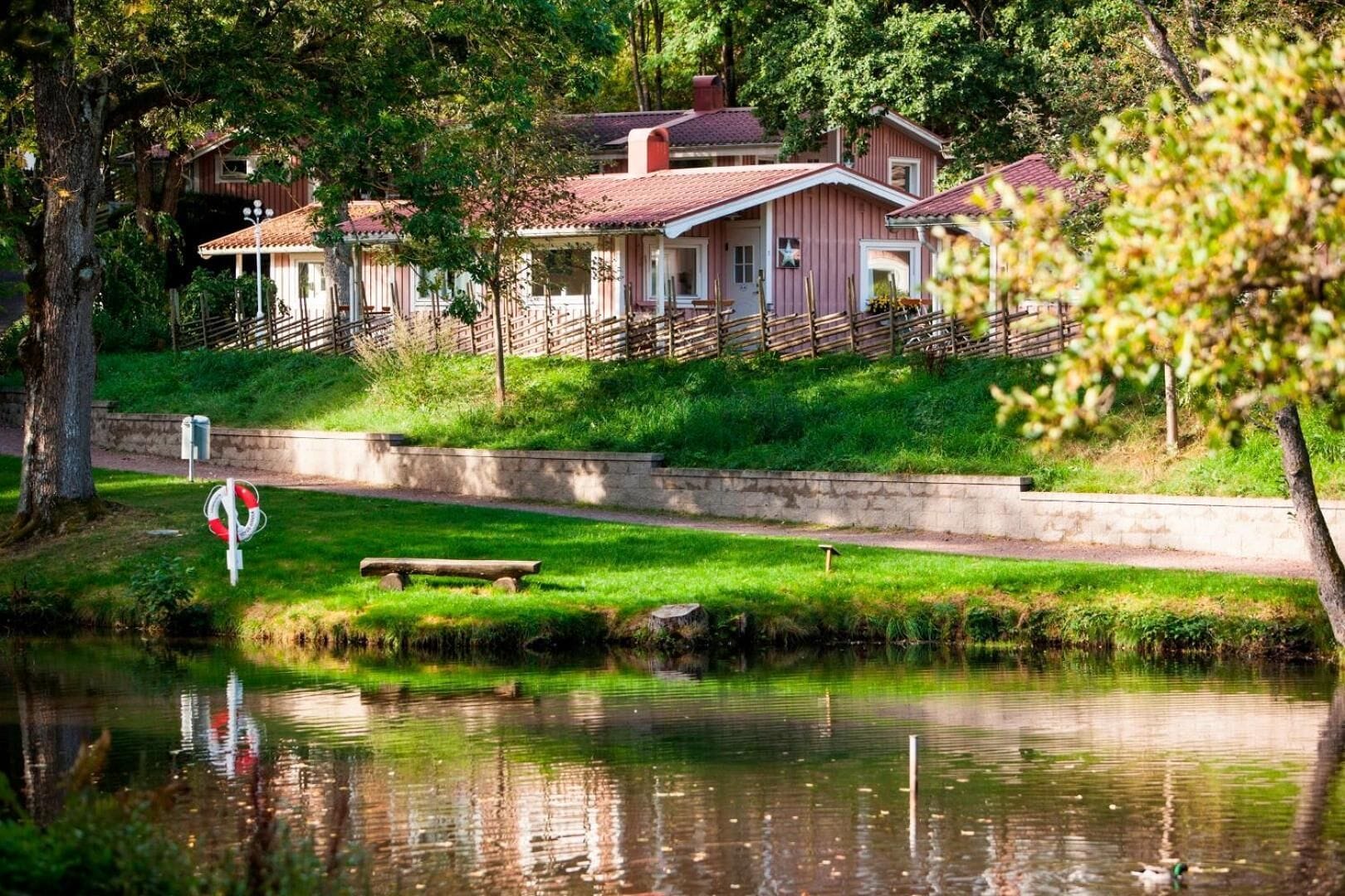 A row of houses with a grassy area and a body of water in the foreground.