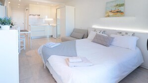 A modern bedroom with a large bed, a ceiling fan, a painting, and a view of the kitchen. - Central with sea views from the terrace. Pool and free wifi. (Puerto de la Cruz)