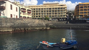 A boat docked at a harbor with a stone wall and buildings in the background. - Central with sea views from the terrace. Pool and free wifi. (Puerto de la Cruz)
