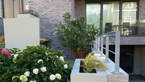 A modern building with a brick facade, large windows, and a balcony with potted plants. - Apartment Sontje the first time OG (Laboe)