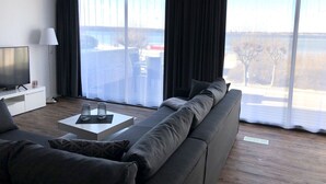 A modern living room with a large grey sofa, a flat-screen TV, and a coffee table. - Apartment Sontje the first time OG (Laboe)
