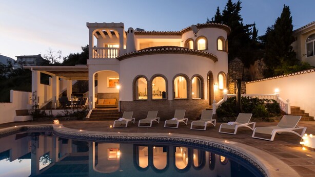 Ein luxuriöses Haus mit Swimmingpool, Sitzgelegenheiten im Freien und einem gut beleuchteten Innenraum.