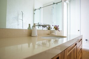 A bathroom with a large mirror, a sink, and a shower. - Modern & Stylish 3BR Apt With Balcony (Tel Aviv)