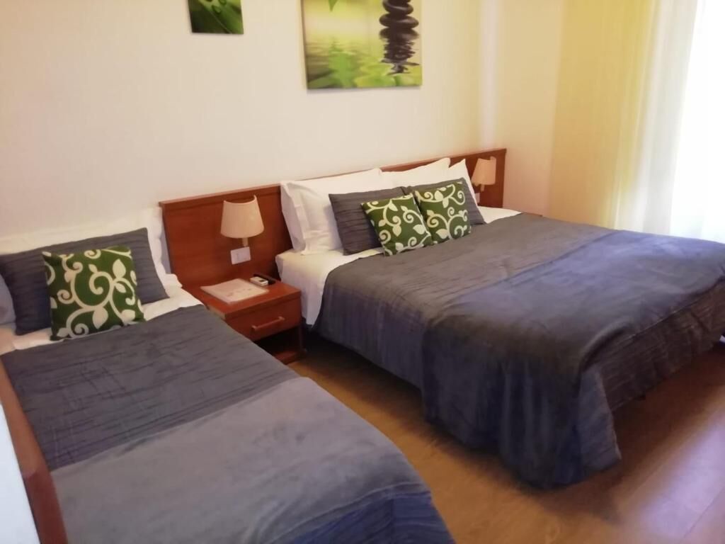 Habitación de hotel con dos camas individuales, una mesita de noche, una lámpara y un cuadro en la pared.