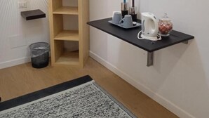 Een kamer met een houten laddenplank, een zwart aanrecht met een waterkoker, een beker en een kaarshouder.