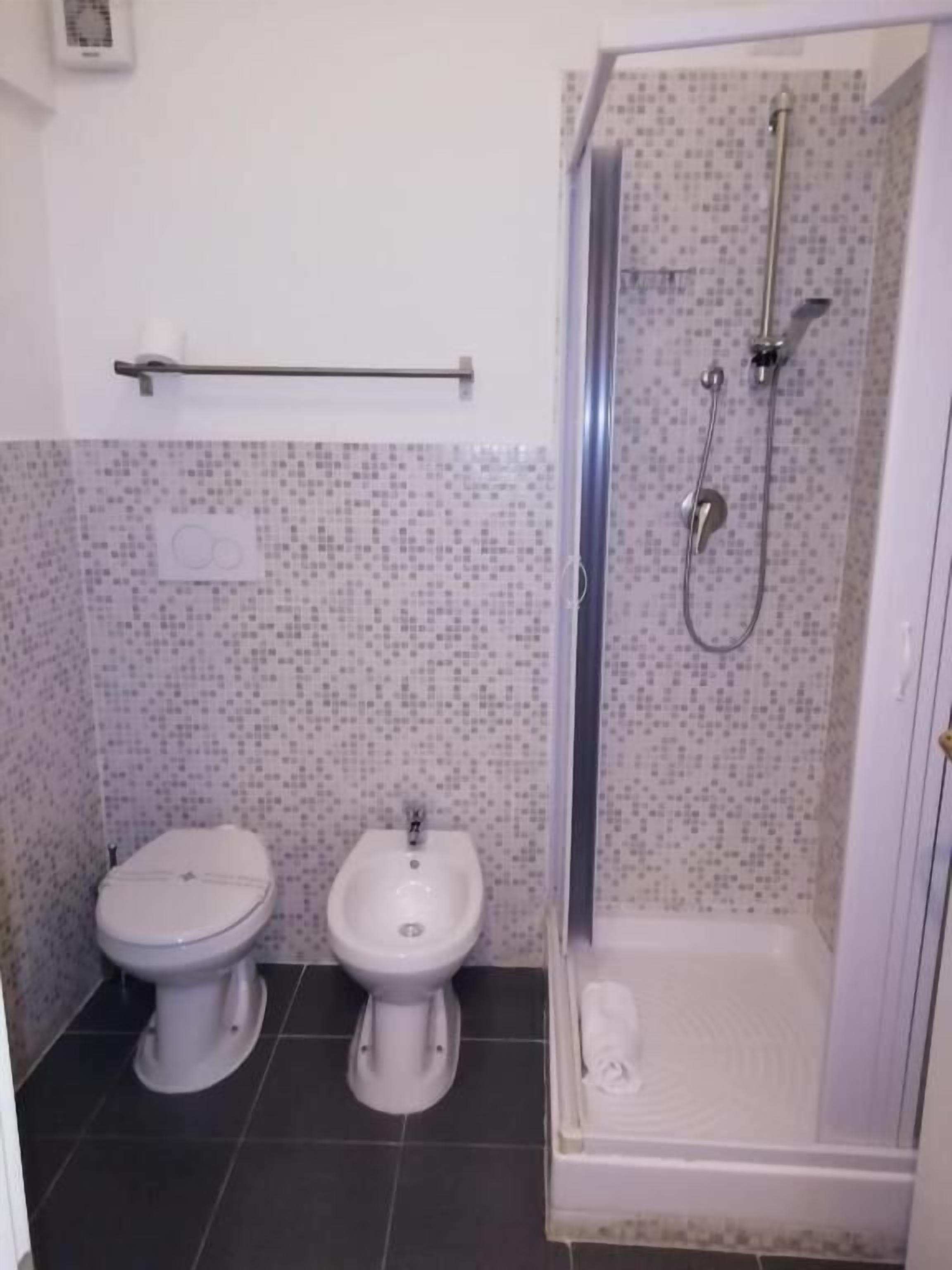 A bathroom with a toilet, bidet, and a glass-enclosed shower area.