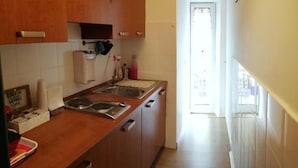 Een keuken met houten kastjes, een roestvrijstalen spoelbak en een inbouwfornuis.
