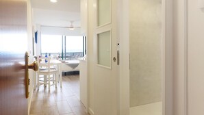 Ein Hotelgang mit Holzboden, weißen Wänden und einer Tür zu einem Balkon mit Aussicht.
