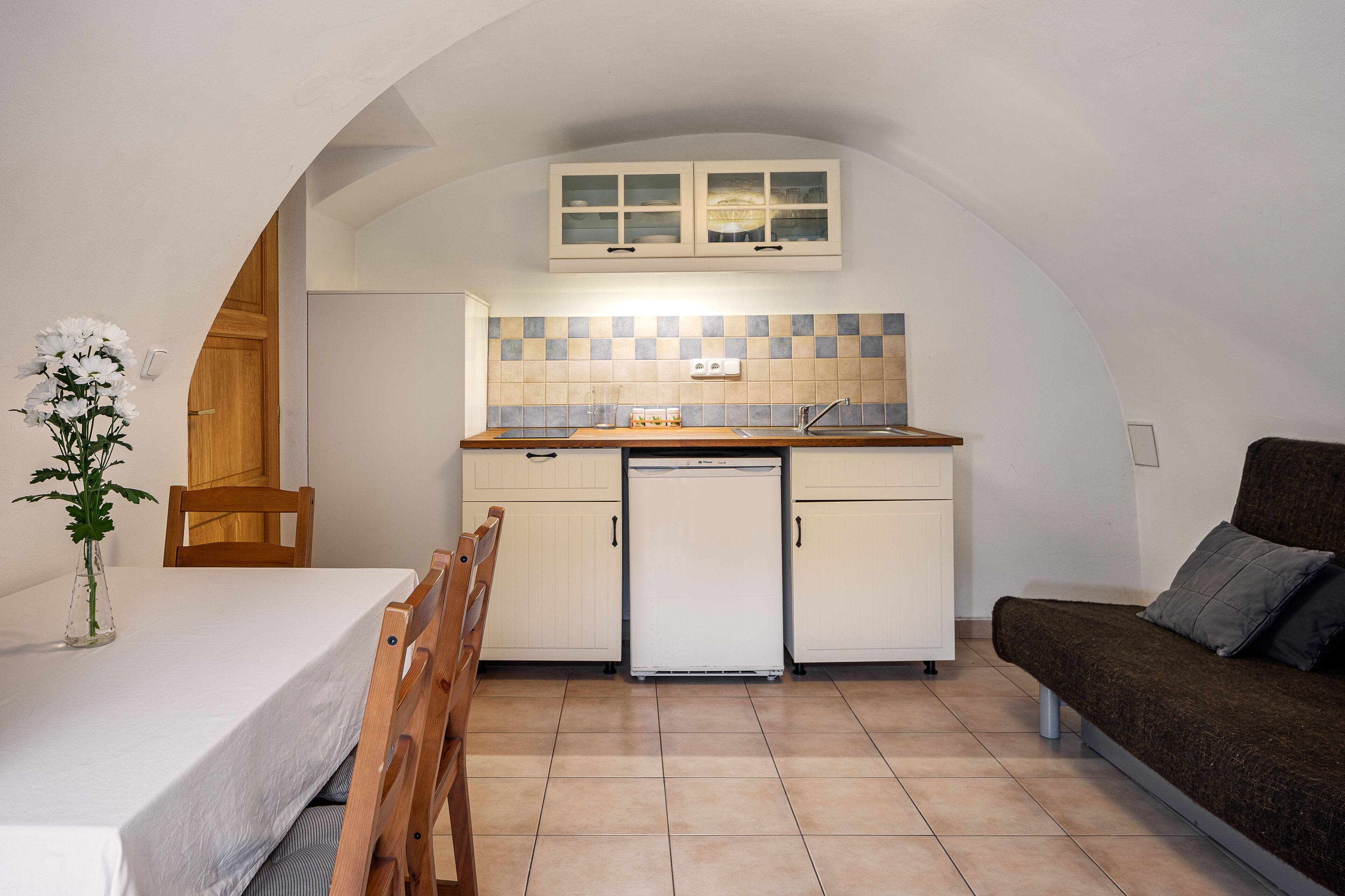 A compact kitchen with white cabinets, a built-in oven, and a small refrigerator.