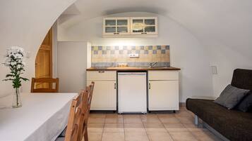 A compact kitchen with white cabinets, a built-in oven, and a small refrigerator.