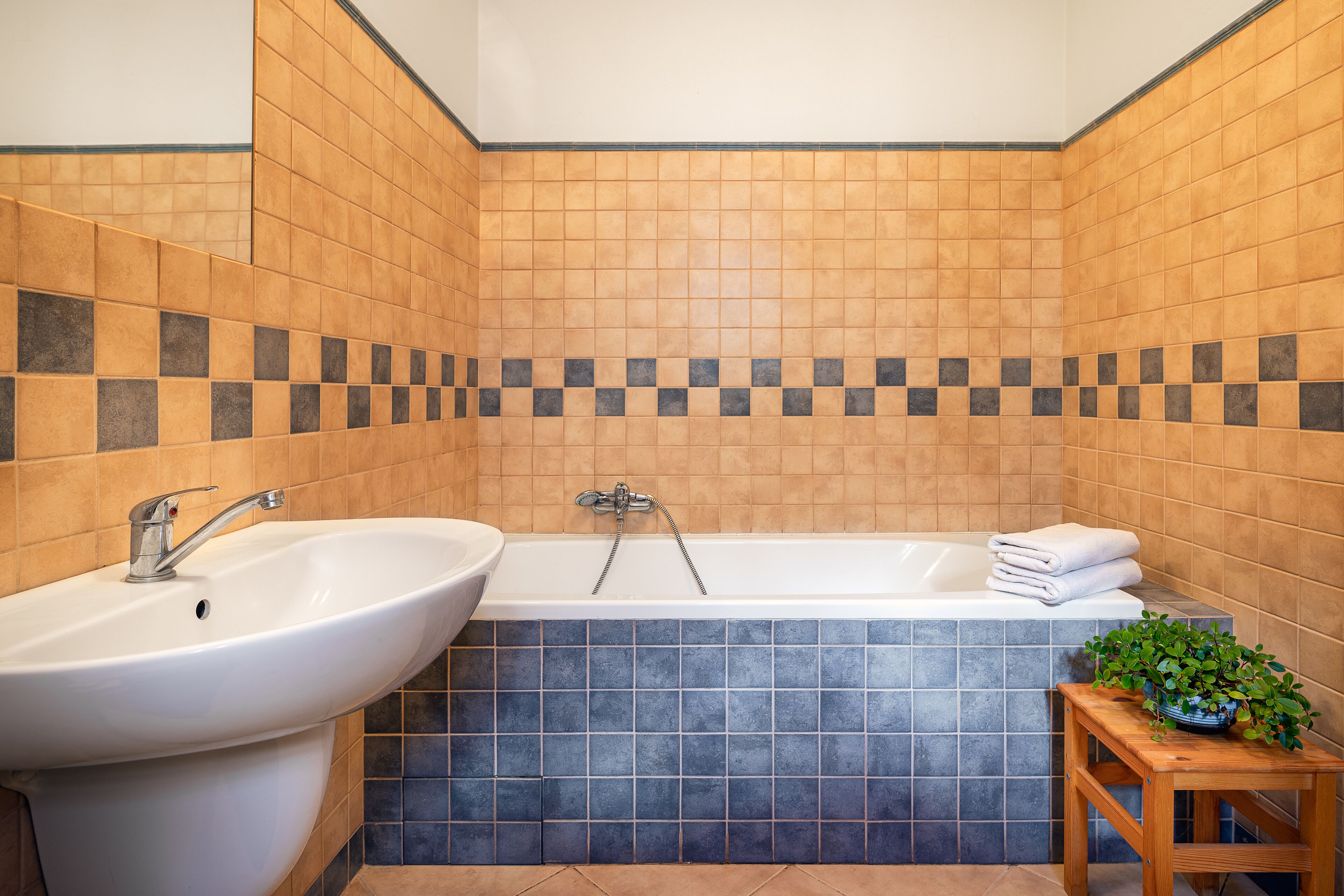 Ein Badezimmer mit Waschbecken, Badewanne und einem kleinen Tisch mit einer Pflanze.