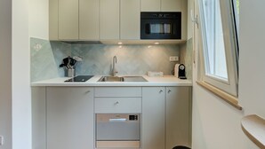 A compact kitchen with a built-in oven, a coffee machine, and a dishwasher. - Studio 4* center near Kirchberg, quiet with view (Luxembourg)
