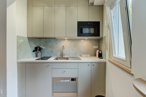 A compact kitchen with a built-in oven, a coffee machine, and a dishwasher.
