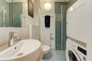A modern bathroom with a sink, toilet, and washing machine.