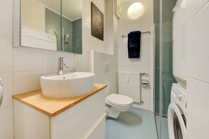 A modern bathroom with a white sink, toilet, and glass shower enclosure. - Studio 4* center near Kirchberg, quiet with view (Luxembourg)