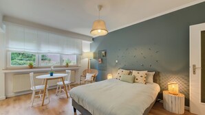 A bedroom with a bed, bedside tables, a window with curtains, a chair, and a lamp. - Studio 4* center near Kirchberg, quiet with view (Luxembourg)