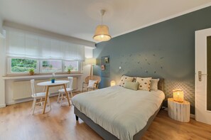 A bedroom with a bed, bedside tables, a window with curtains, a chair, and a lamp.