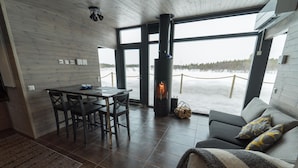 Um interior moderno com lareira, área de jantar e vista para uma paisagem nevada.