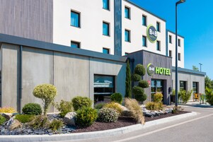 Un hotel tipo B&B moderno con un jardín cuidado, ventanas amplias y un cielo despejado.