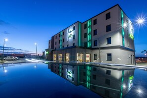 A modern hotel with a reflective pool in front, featuring a prominent 'HOTEL' sign. - B&B HOTEL Troyes Magasins d'usine (Lavau)