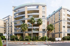 A multi-story building with balconies, palm trees, and a clear sky.