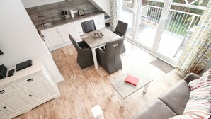 En moderne stue med en grå sofa, et lille sofabord og et spiseområde med et bord og stole.