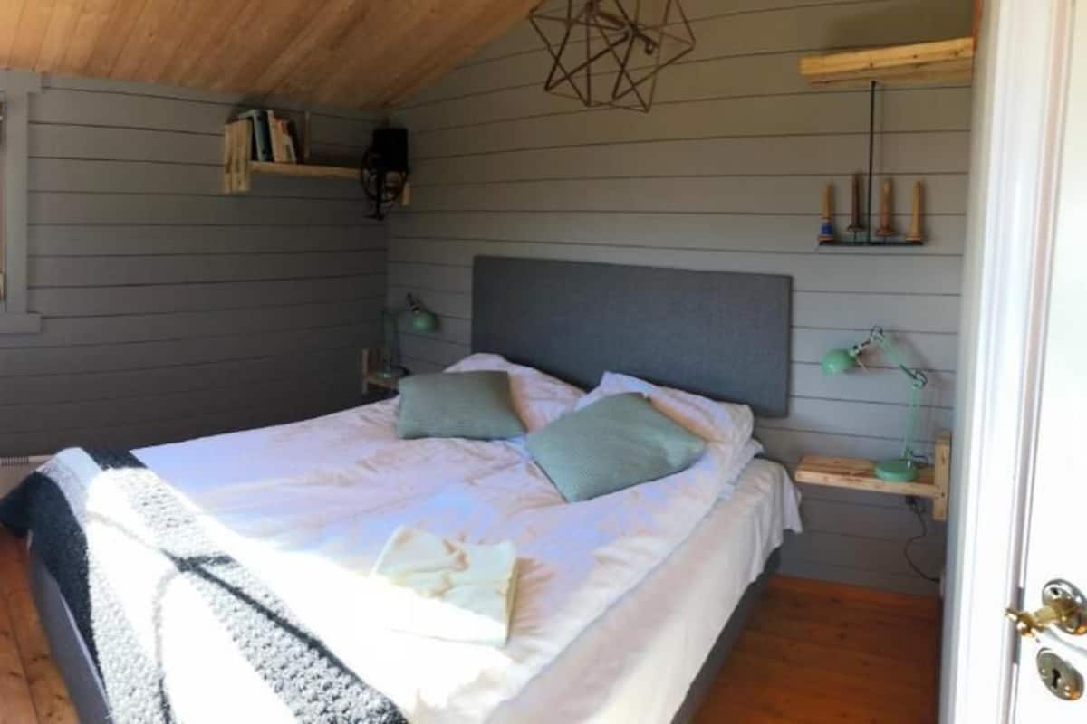 A bedroom with a bed, a chair, a desk, and a window.