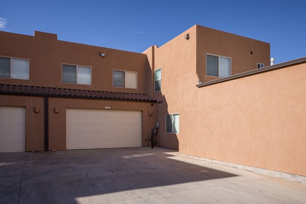 A two-story building with a garage and a small courtyard. - Townhome Near Ntl Parks & Town | Pool & Hot Tub (Moab)