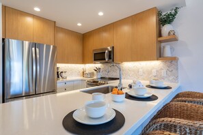 Une cuisine moderne dotée d’appareils électroménagers en acier inoxydable, de meubles en bois et d’un dosseret de carrelage disposé en motif chevron.