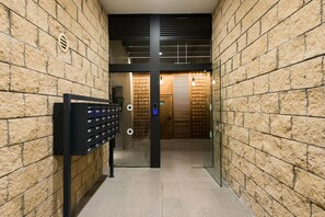 A hallway with brick walls, a metal gate, and a wooden door at the end. - Contemporary & Texture-Rich Hideaway (Tel Aviv)