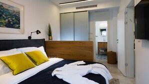 Quarto moderno com uma cama grande, cabeceira de madeira e mesa de cabeceira com abajur.