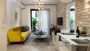Uma sala de estar moderna com um sofá amarelo, uma mesa de centro redonda e um espaço de jantar com uma mesa e cadeiras brancas.