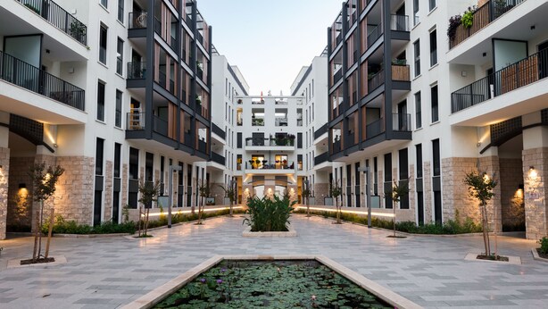 Um edifício moderno com um pátio central que apresenta um jardim aquático com folhas de nenúfar e uma fonte.