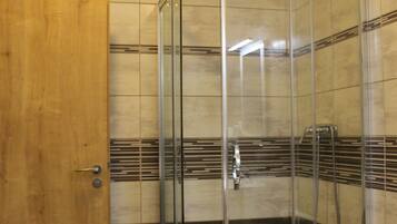 Un baño con ducha de vidrio, inodoro blanco y puerta de madera.
