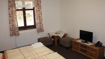 Ein Hotelzimmer mit einem Bett, einem kleinen Tisch mit Fernseher, einem Telefon und zwei Hocker.