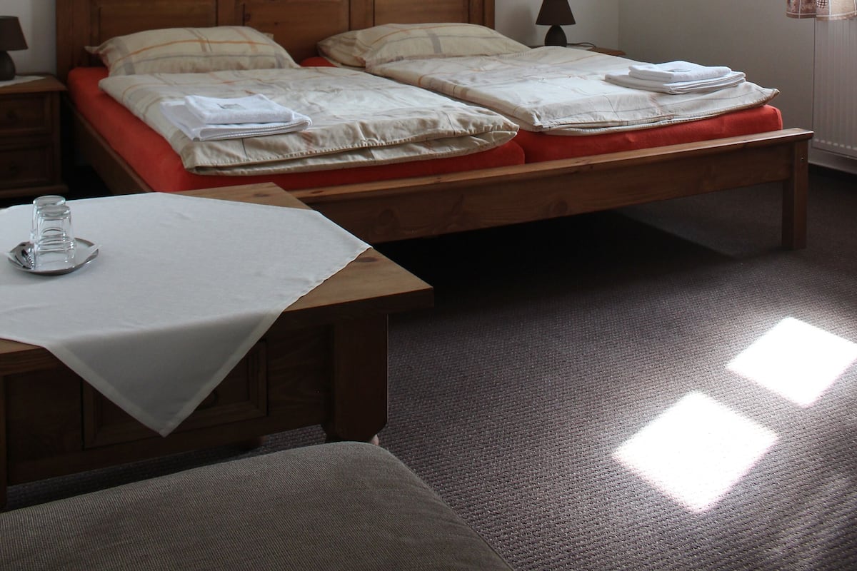 Ein Schlafzimmer mit einem Doppelbett, einem Nachttisch mit Lampe und einem Fenster mit Vorhängen.