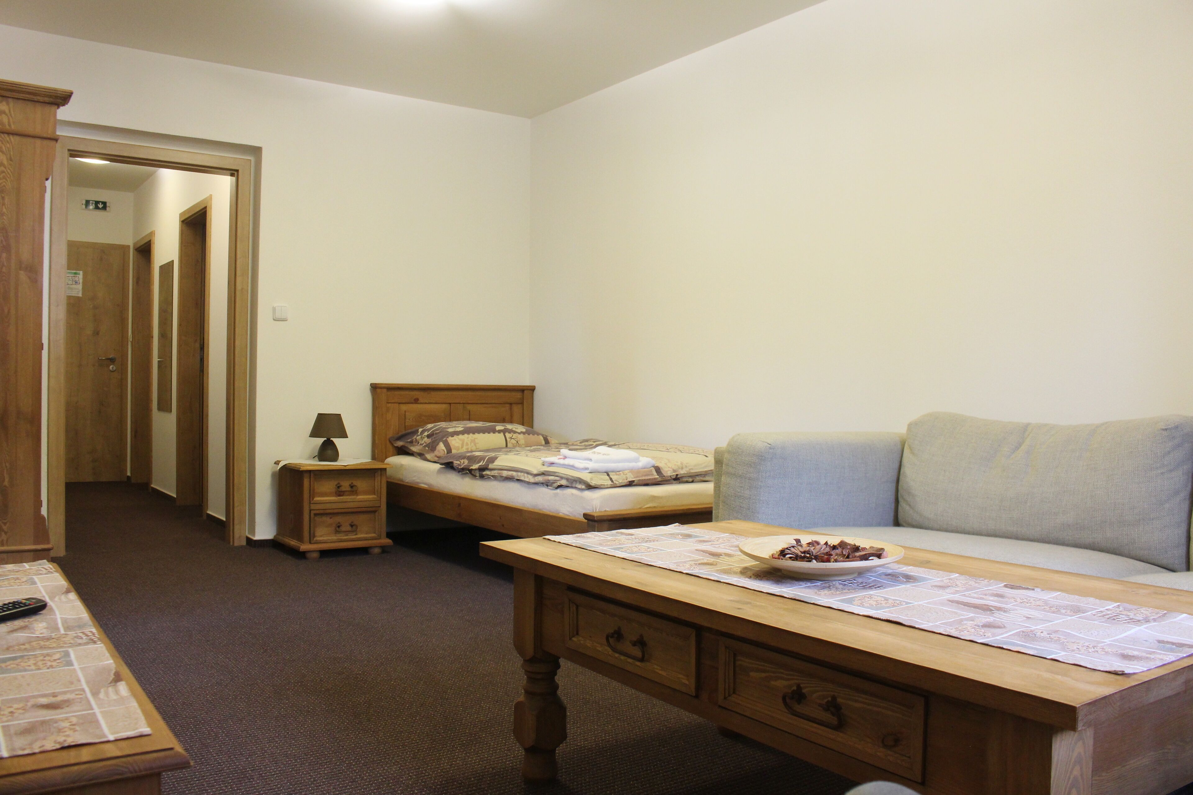 A bedroom with a single bed, a nightstand, a desk with papers, and a chair.