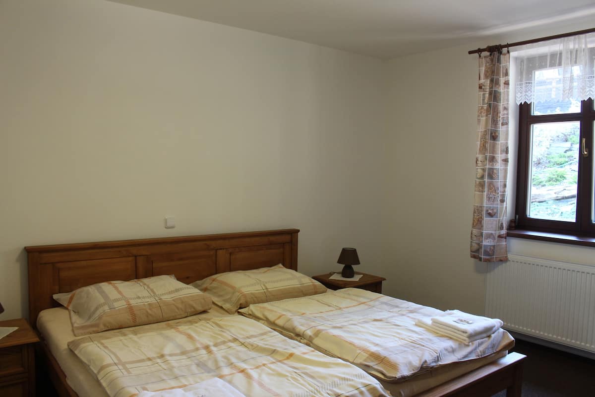 Ein Schlafzimmer mit einem Doppelbett, einem Nachttisch mit Lampe und einem Fenster mit Vorhang.