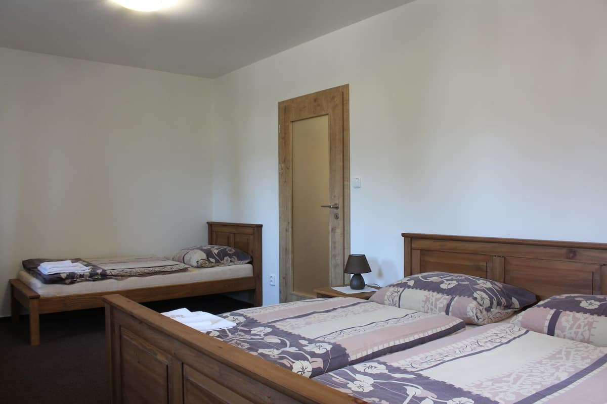 Ein Schlafzimmer mit zwei Einzelbetten, einem Holzkopfteil, einem Nachttisch mit Lampe und einer Tür.