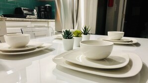 Un plan de travail de cuisine avec des assiettes blanches, des bols et de petites plantes en pot.